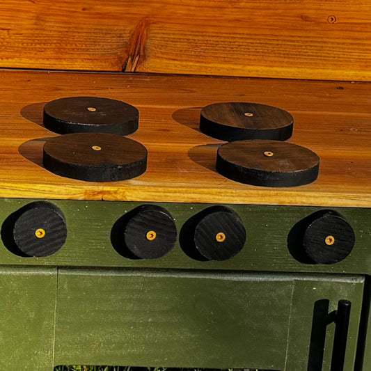 Wooden and green cabinet with round black knobs on a wooden surface